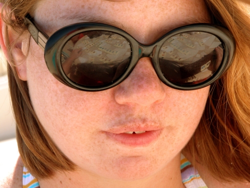 a freckled redhead with the reflection of Rummikub tiles in her sunglassies
